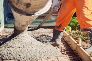 Worker Laying Down Ready Mix Concrete Out of Pipe