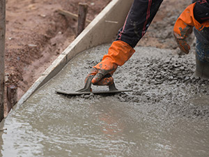 Man in Orange Gloves Smoothing Out Concrete