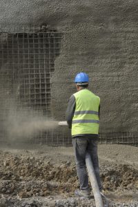 Worker Spraying Gunnite Concrete onto Wall