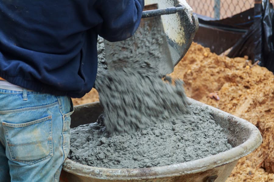 man directing concrete being poured into a wheelbarrow